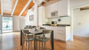 Cozinha moderna com armários brancos, micro-ondas e fogão. Há uma mesa de jantar com quatro cadeiras.