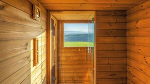 Ein holzgetäfelter Innenflur mit einer Glastür, die auf eine grüne Landschaft hinausführt.