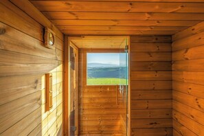 Ein holzgetäfelter Innenflur mit einer Glastür, die auf eine grüne Landschaft hinausführt.
