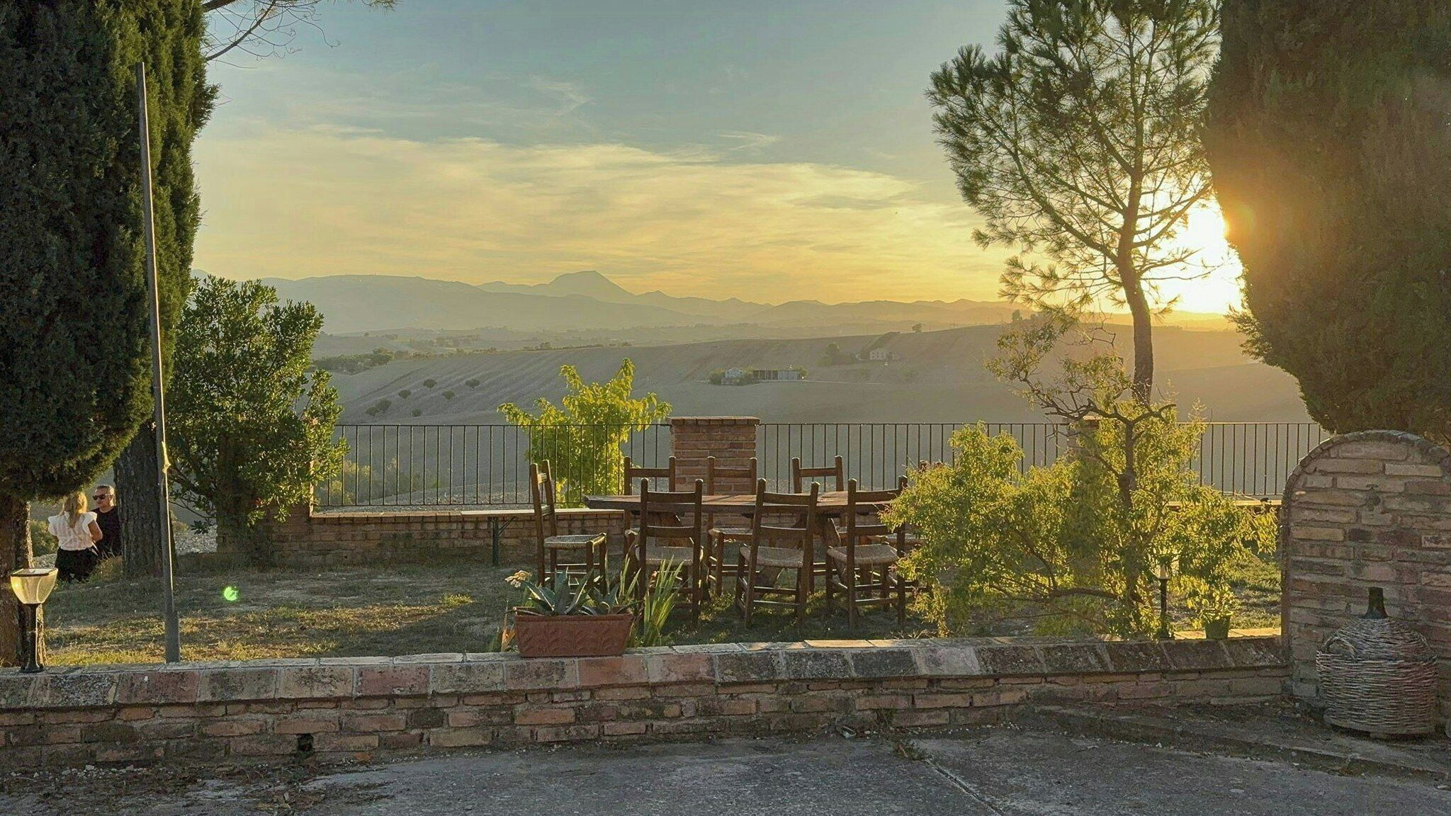 A patio with outdoor furniture, a stone wall, and a view of distant hills.