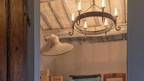 Ein Zimmer mit Bett, Holzboden, einer Chandelüster und Blick durch eine offene Tür auf einen Außenbereich.