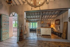 A rustic kitchen with a wooden island, a bench, and a hanging light fixture. - Historic farmhouse with loggia in Cortona (Cortona)