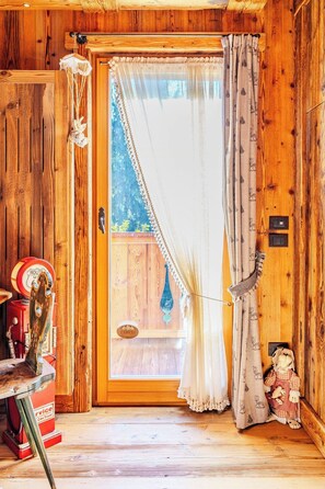 Ein Holzhütten-Interieur mit einer Tür, einem kleinen Tisch mit einem roten Gegenstand und einer Puppe.