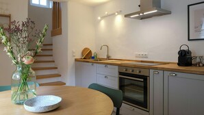 A modern kitchen with a wooden table, a vase with flowers, and a built-in oven. - Tower house with two terraces in Bad Münstereifel (Bad Münstereifel)