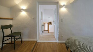 A room with a wooden floor, a bed with a checkered bedspread, a chair, and two wall-mounted lights. - Tower house with two terraces in Bad Münstereifel (Bad Münstereifel)