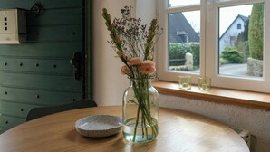 A round wooden table with a glass vase containing flowers, a speckled bowl, and a window with a view of houses. - Tower house with two terraces in Bad Münstereifel (Bad Münstereifel)