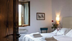 Een hotelkamer met een bed, een stoel, een raam en een aan de muur hangend schilderij.