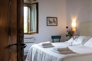 A hotel room with a bed, a chair, a window, and a wall-mounted picture. - Apartment in Agriturismo with wellness in Maremma (Massa Marittima)