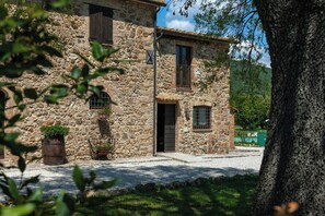 A stone building with a wooden door, windows, and a small balcony. - Apartment in Agriturismo with wellness in Maremma (Massa Marittima)
