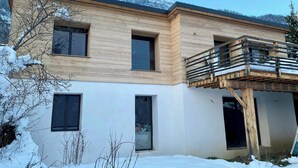 Ein modernes, zweistöckiges Gebäude mit Holzfassade, großen Fenstern und einem Balkon.