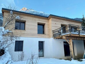 Un bâtiment moderne à deux étages, doté d’une façade en bois, de grandes fenêtres et d’un balcon.