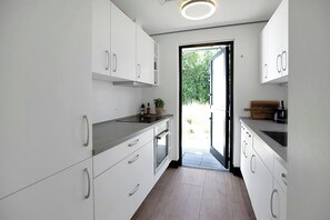 A modern kitchen with white cabinets, a built-in oven, and a wooden countertop. - Family oasis near nature, beach & Sommerland (Højby)