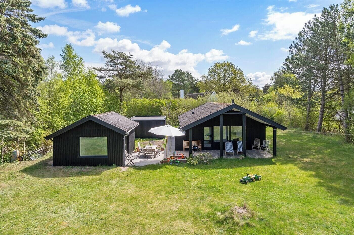 A modern house with a patio, a covered outdoor seating area, and a lawn.