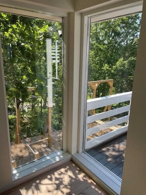 A room with a large window, a wooden deck outside, and a white railing. - Tranquil gem with sea view near Ebeltoft (Ebeltoft)