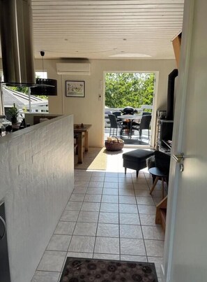 A kitchen with a stove, a dining area with a table and chairs, and a view of the outdoors. - Tranquil gem with sea view near Ebeltoft (Ebeltoft)