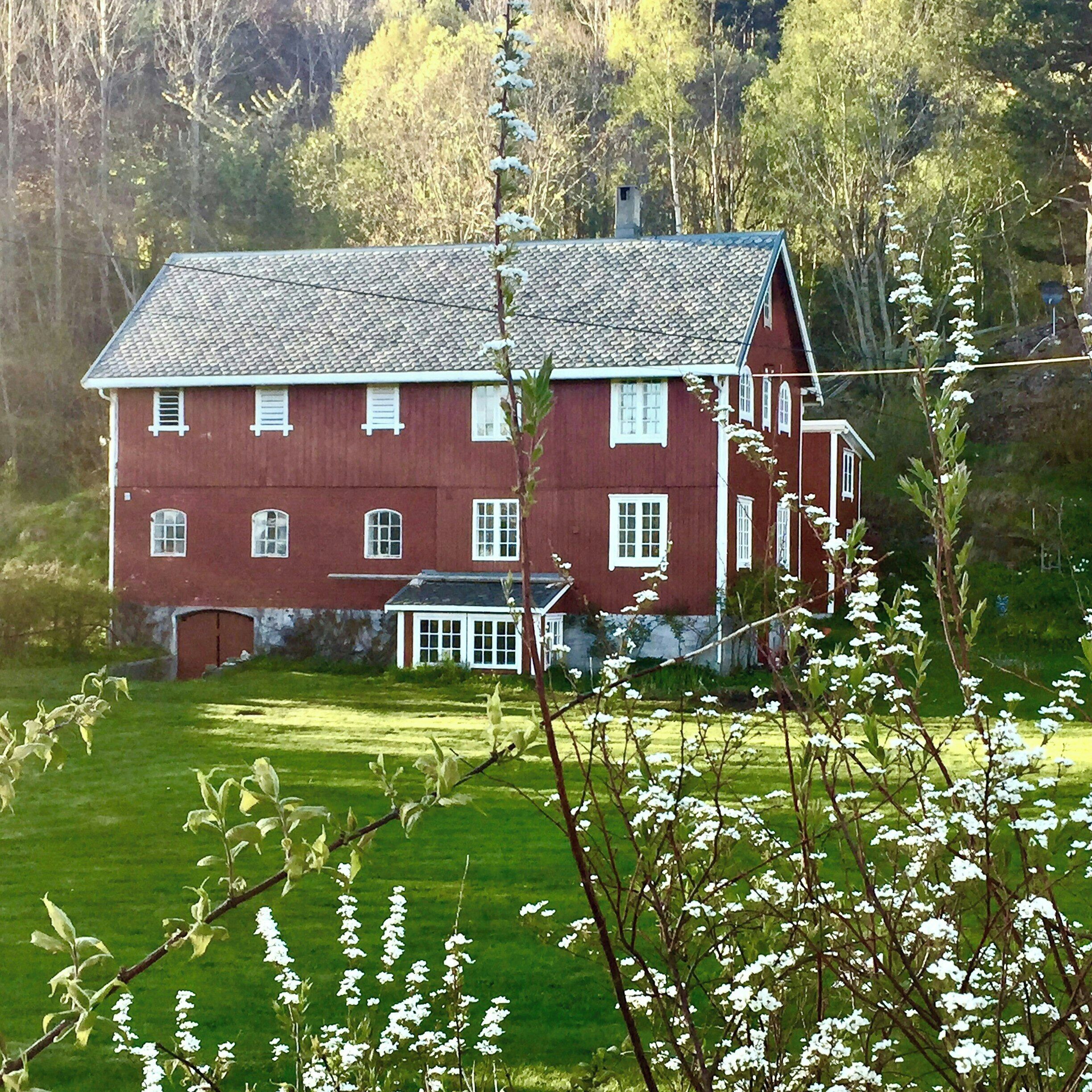 A large, red, two-story house with a white porch and a small attached structure.