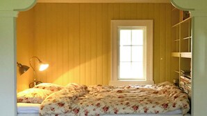 Um quarto com cama, janela e estante com livros.