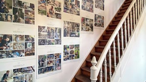 Una escalera con barandal de madera y una pared decorada con varias fotografías enmarcadas.