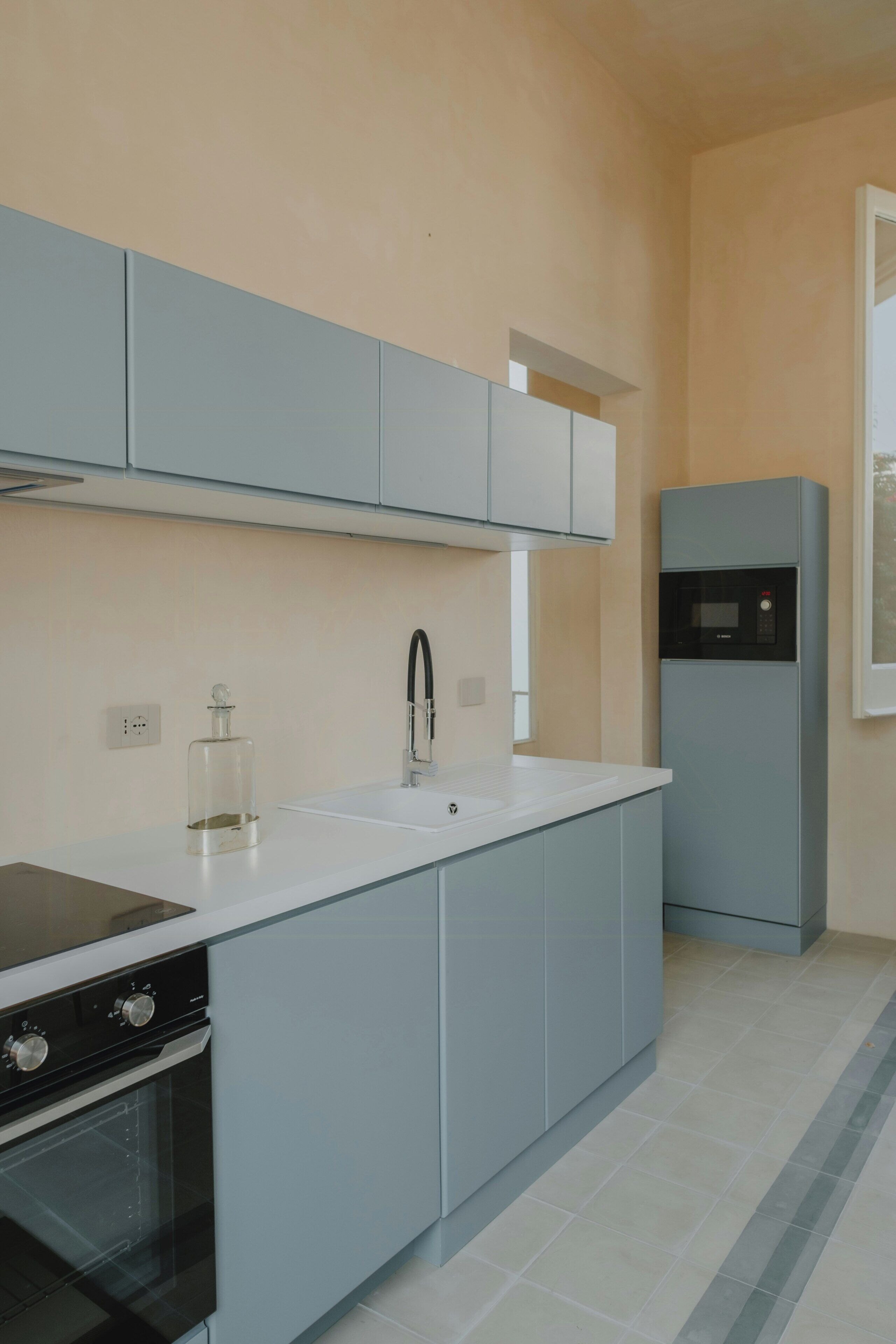 A modern kitchen with grey cabinets, a black stove, and a built-in microwave.