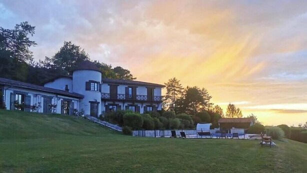 A large, multi-story building with a white facade, a balcony, and a grassy slope leading up to the entrance. - Apartment in villa with shared pool in Razac (Razac-sur-l'Isle)