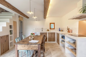 Eine Küche mit Holztisch, Stühlen und einer eingebauten Kochinsel mit Spüle und Stauraum.