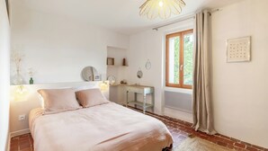 A bedroom with a bed, bedside table, mirror, and a window with curtains. - House with private beach on the Sorgue (L'Isle-sur-la-Sorgue)