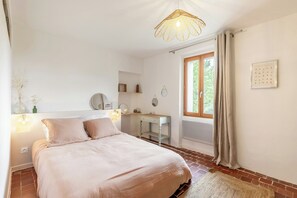 Ein Schlafzimmer mit Bett, Nachttisch, Spiegel und einem Fenster mit Vorhängen.