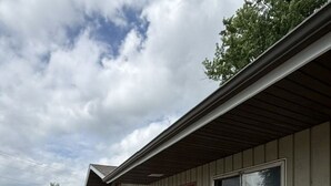 A motel with a row of rooms, a parking lot, and a clear sky. - The Village Motel (Cambridge)