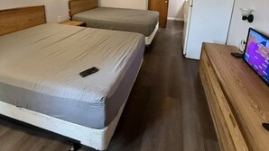 A hotel room with two beds, a wooden dresser, a television, and a refrigerator. - The Village Motel (Cambridge)
