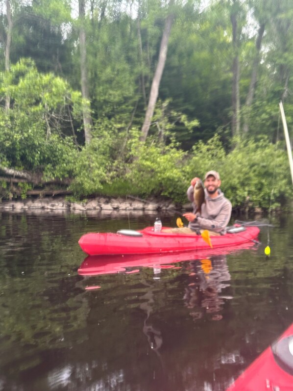 A red kayak on calm water with greenery in the background.