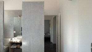 Uma casa de banho moderna com um espelho grande, uma pia e uma sanita. Há um porta-toalhas com toalhas.