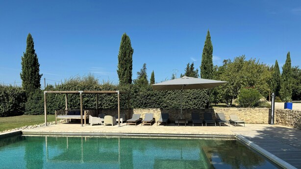 Piscina com espreguiçadeiras e pérgola.