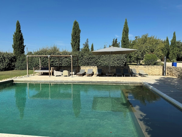 Ein Swimmingpool mit Liegestühlen und einer Pergola.