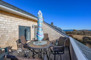 A deck with a table and chairs, an umbrella, and a view of the landscape.
