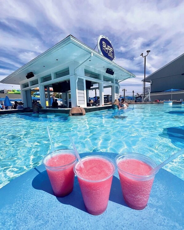 A pool area with a covered seating area and a sign reading 'SURF HOUSE.'