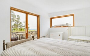 Un dormitorio con cama, mesita de noche, cómoda y ventana, con vistas al exterior.