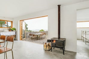 Un interior moderno con una estufa de leña, un comedor y vistas al exterior.