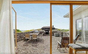 Un patio con mobiliario exterior, un muro de piedra y vistas a una colina.