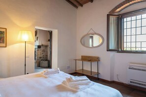 Ein Schlafzimmer mit einem Bett, einer Nachttischlampe, einem Spiegel, einem Fenster und einer Heizung.