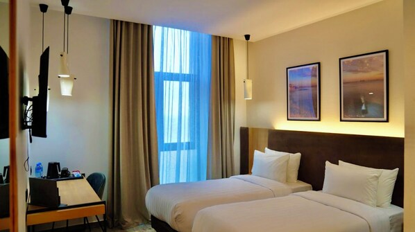 A hotel room with two beds, a desk with a chair, a TV mounted on the wall, and two framed pictures. - Yot Hotel Algiers (Algiers)