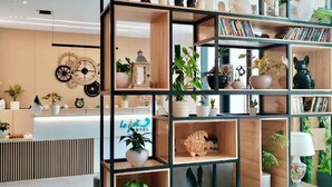A modern hotel lobby with a central wooden bookshelf, a reception desk, and potted plants. - Yot Hotel Algiers (Algiers)