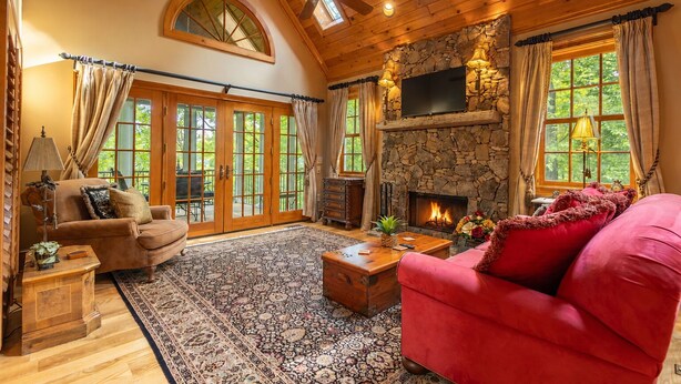 Un salon chaleureux avec une cheminée, un plafond en bois et de grandes fenêtres.
