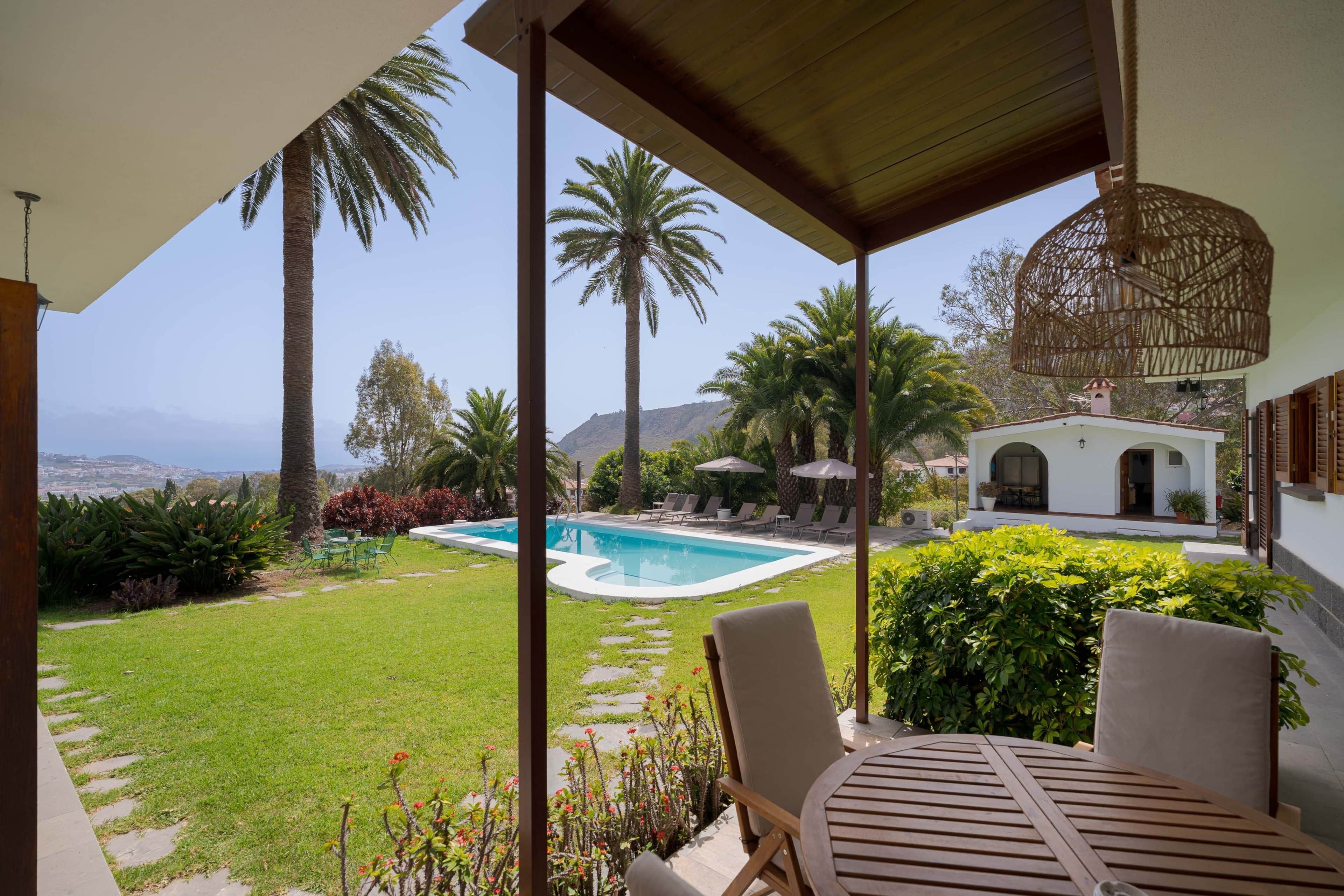 Uma área de piscina com espreguiçadeiras, um pérgola e vista para o oceano.