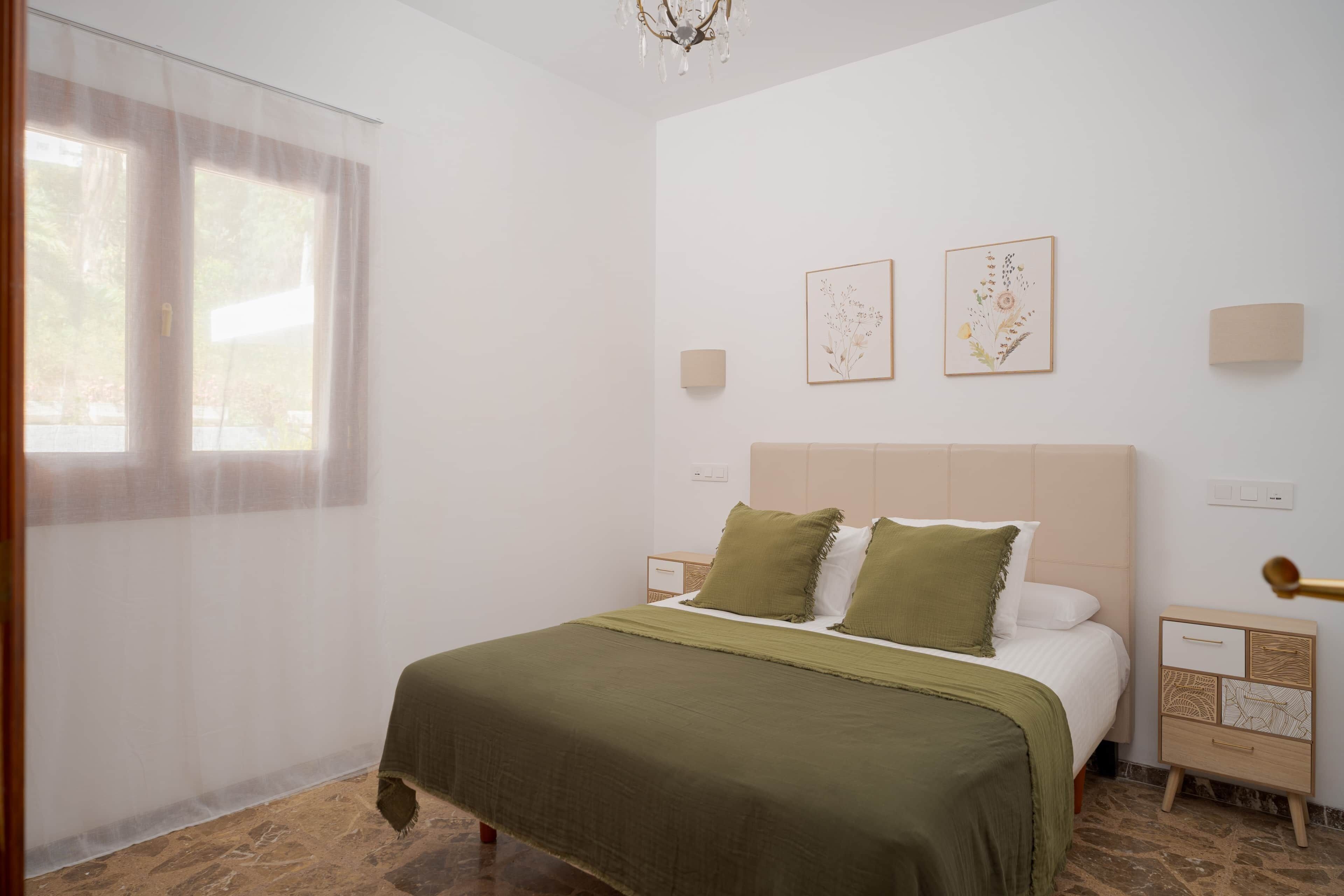 Een slaapkamer met een bed, nachtkastjes, een pronkstuk en kunst aan de muur.