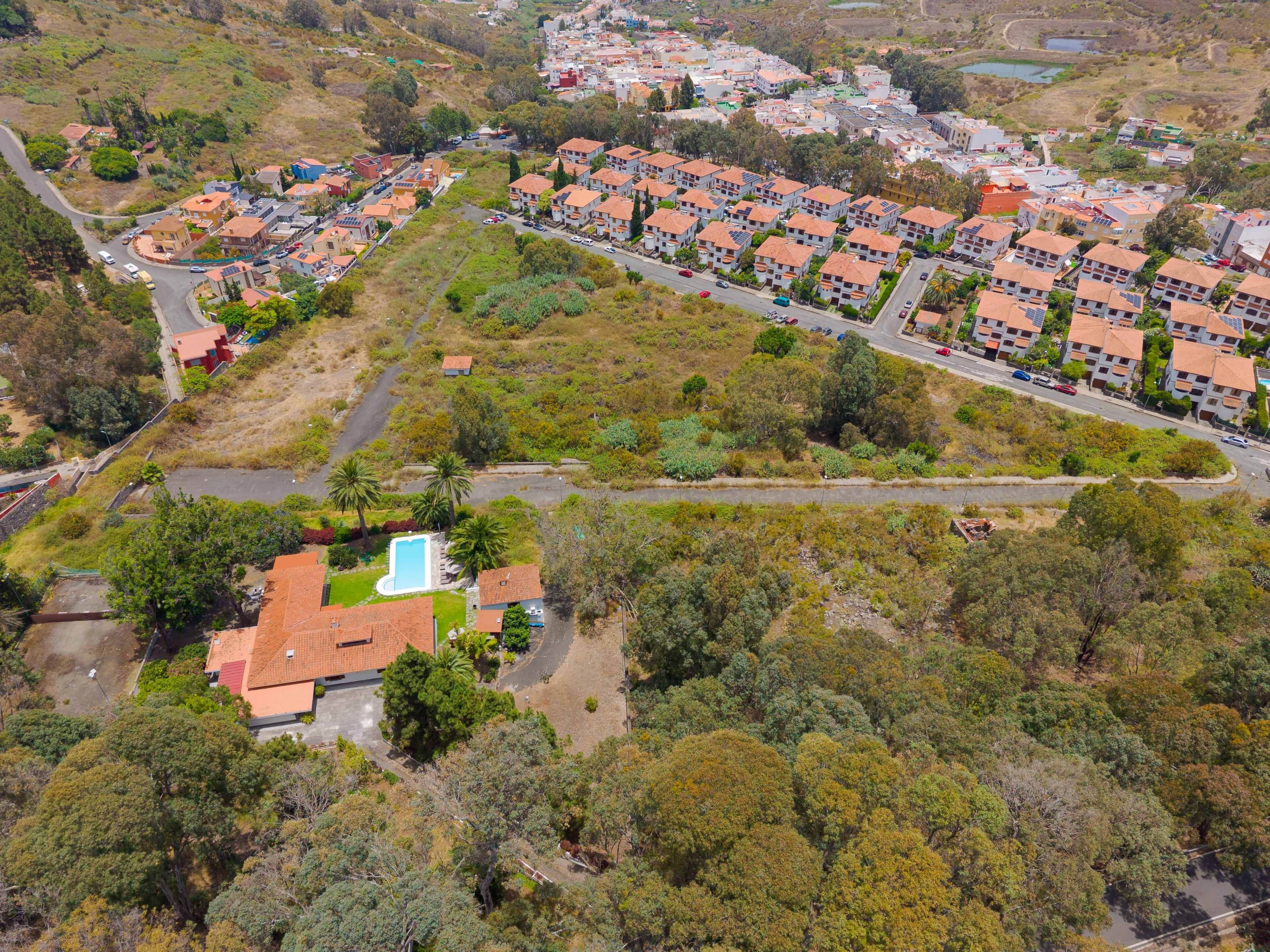 Vista aérea de uma área residencial com vários edifícios de apartamentos, uma piscina e vegetação ao redor.