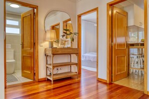 A room with wooden flooring, a mirror, a wooden shelf, a bed, and a table with stools. - Funchal Infinity, a Home in Madeira (Funchal)