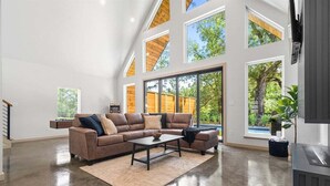 A spacious living room with a large sectional sofa, a coffee table, and a fireplace. - A-Frame Retreat with Pool, Hot Tub, Lake Access (Garland County)