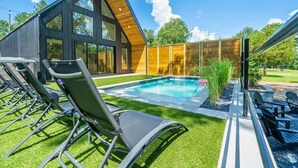 A modern house with a swimming pool, outdoor seating, and a well-maintained lawn. - A-Frame Retreat with Pool, Hot Tub, Lake Access (Garland County)