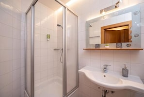A bathroom with a glass-enclosed shower, a white sink, and a mirror with a wooden frame. - Landhaus Zell am See: Cozy Accommodations in a Quiet Location (Zell am See)
