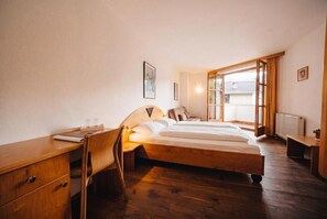 A bedroom with a wooden bed, a desk, a chair, and a window with curtains. - Vrbo Property (Zell am See)